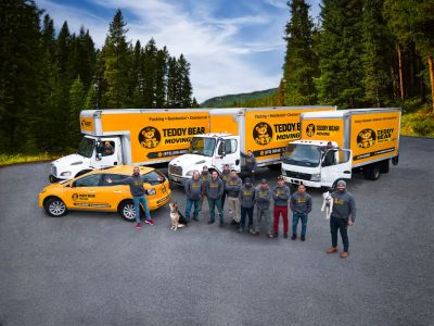 Teddy Bear Moving team alongside their yellow moving trucks